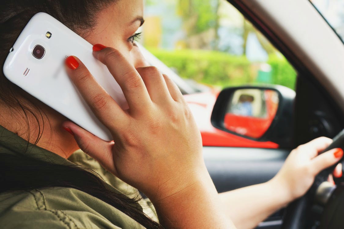 Photo of a woman using a smartphone while driving a car Photo of a woman using a smartphone while driving a car