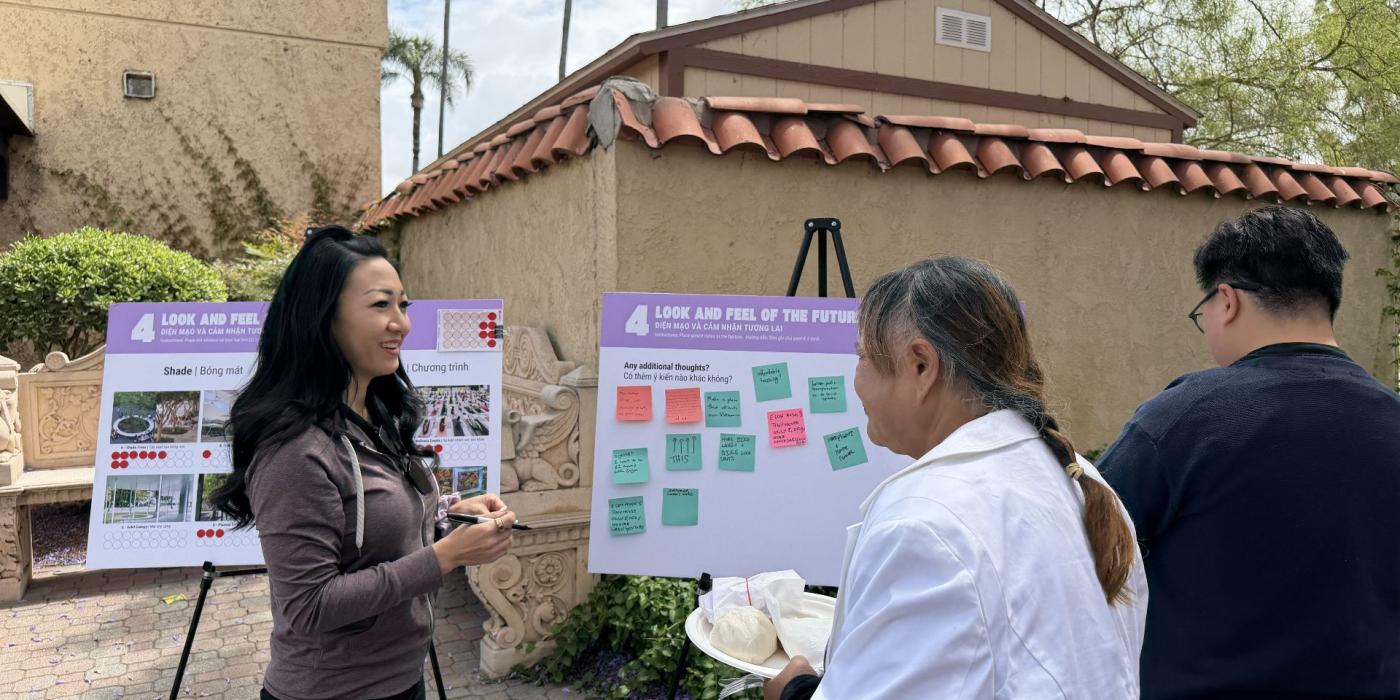 Community members reviewing bilingual "Look and Feel of the Future" planning boards with sticky note feedback at an outdoor public engagement event.