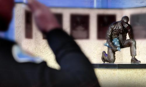 Police officer saluting the Garden Grove police memorial.