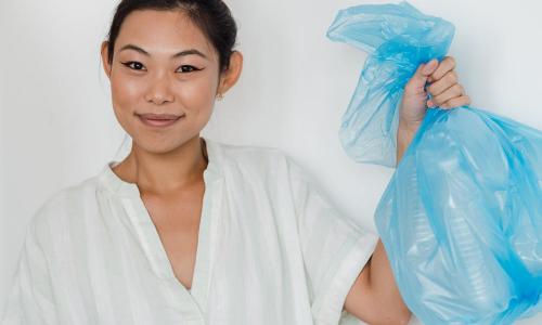 Photo of a young woman holding a recycling bag.